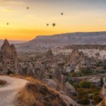 Gün doğumunda Kapadokya vadileri, kaya oluşumları ve sıcak hava balonları
